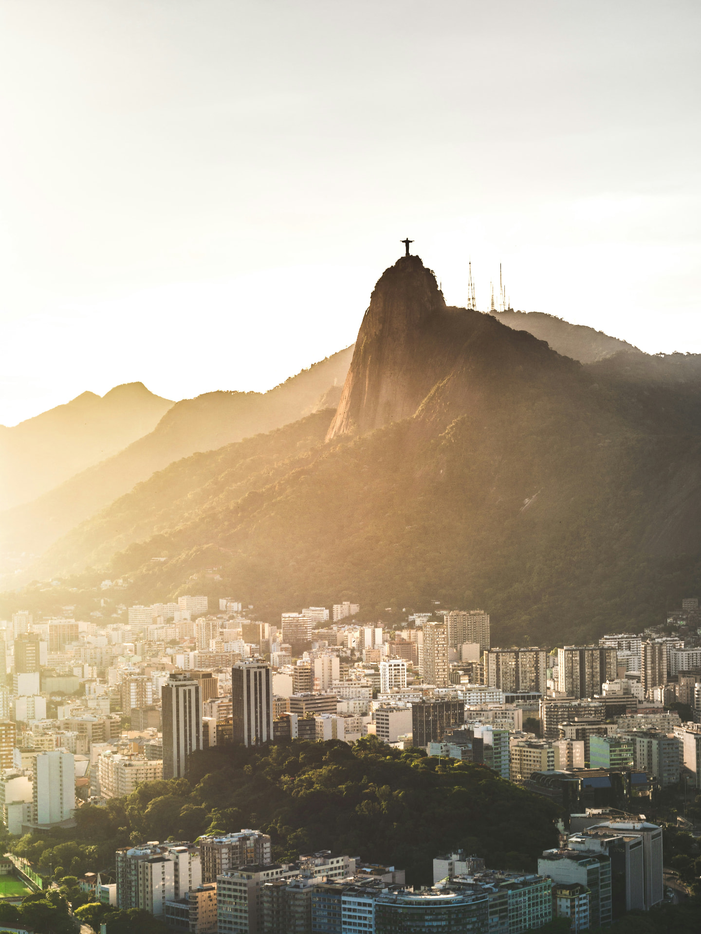 Christ the Redeemer atop Corcovado mountain, rising above Rio de Janeiro in warm golden light