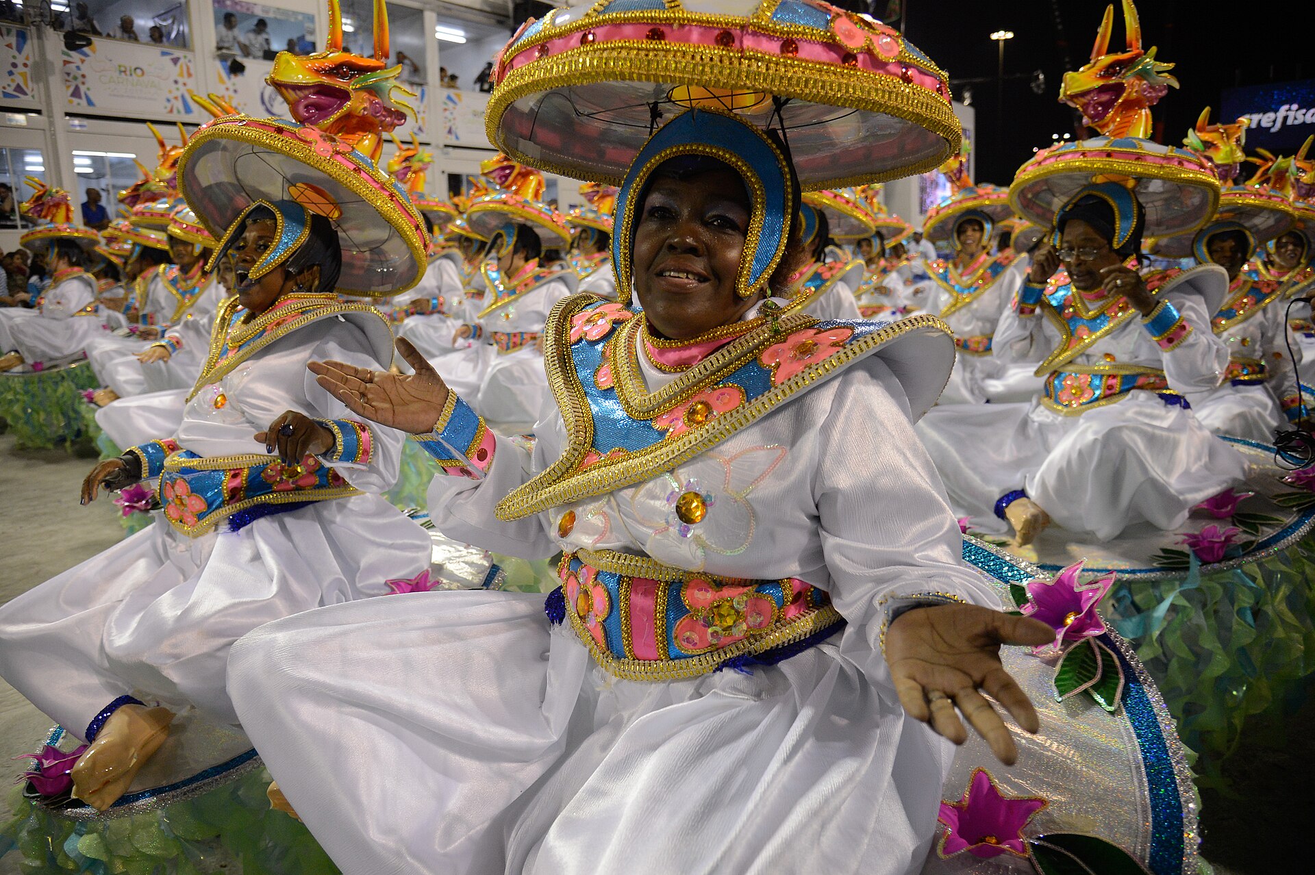 Baianas da Portela com fantasias brancas e douradas desfilando no Sambódromo